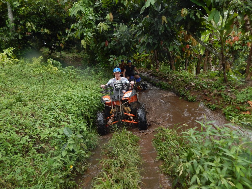 Peserta mengendarai ATV melewati jalur berlumpur dan area pedesaan dalam kegiatan adventure team outing di Bali.