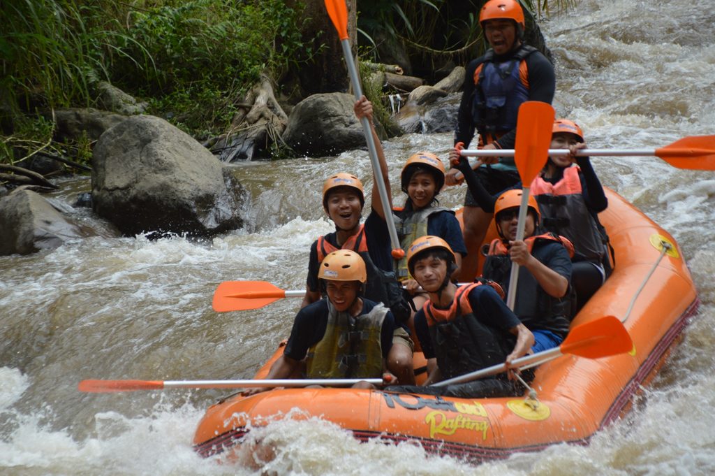 Peserta outing perusahaan melakukan rafting bersama menyusuri Sungai Ayung di Bali.